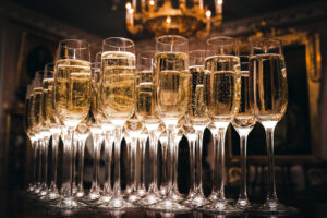 Gefüllte Champagnergläser, von unten beleuchtet, in einem festlichen Saal.