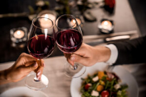 Zwei Menschen stoßen an einem festlich gedeckten Tisch mit Wein an