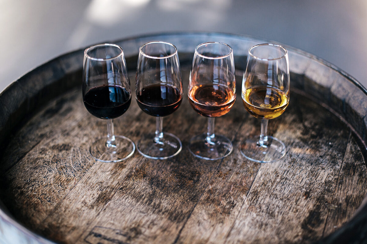 Vier Gläser mit den vier unterschiedlichen Portwein-Stilen auf einem Holzfass