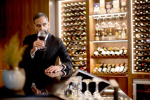 Eleganter Mann riecht an einem Weinglas in einer edlen Bar