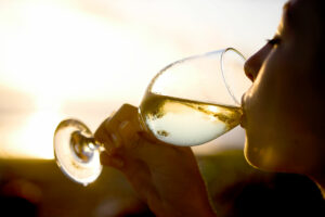 Frau trinkt bei Sonnenuntergang draußen ein Glas Muskateller-Wein