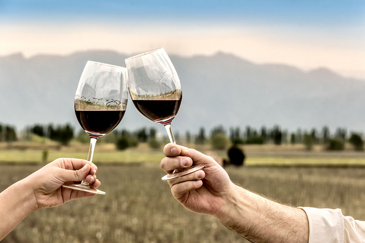 Ein Paar stößt draußen mit zwei Gläsern Rotwein an, in denen sich Amarone della Valpolicella befindet
