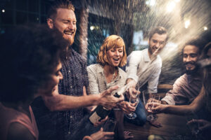 Eine Gruppe junger Menschen feiert mit einer Flasche Schaumwein