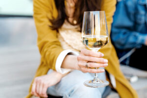 Eine Frau hält ein Glas mit feinherben Weißwein in der Hand